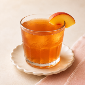 Peach tea in a clear glass on a cream tabletop
